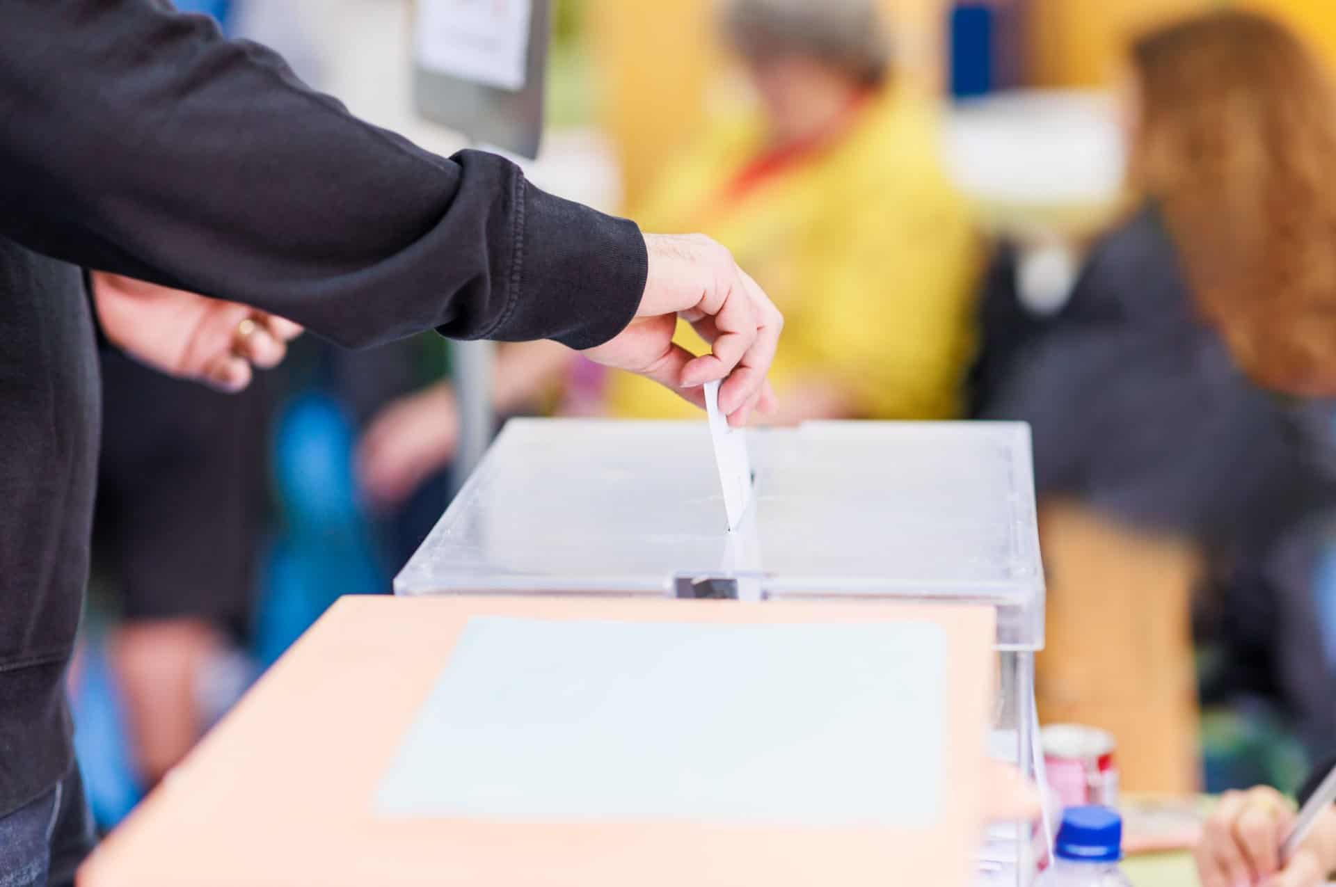 A man voting using a ballot box.