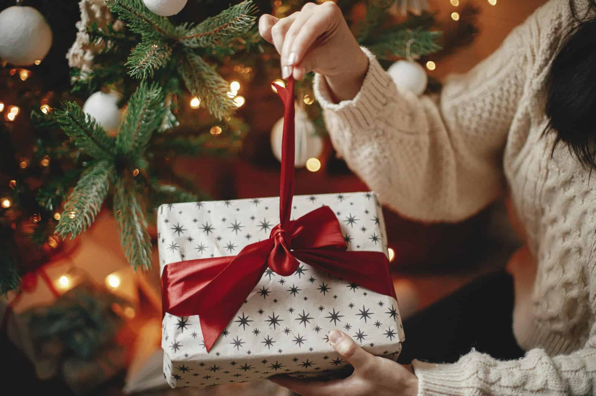 A woman untying a ribbon on a Christmas present.